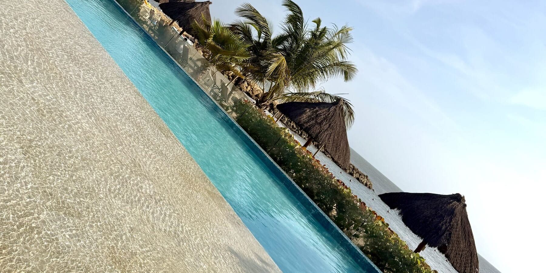 An infinity pool meeting the sand at golden hour